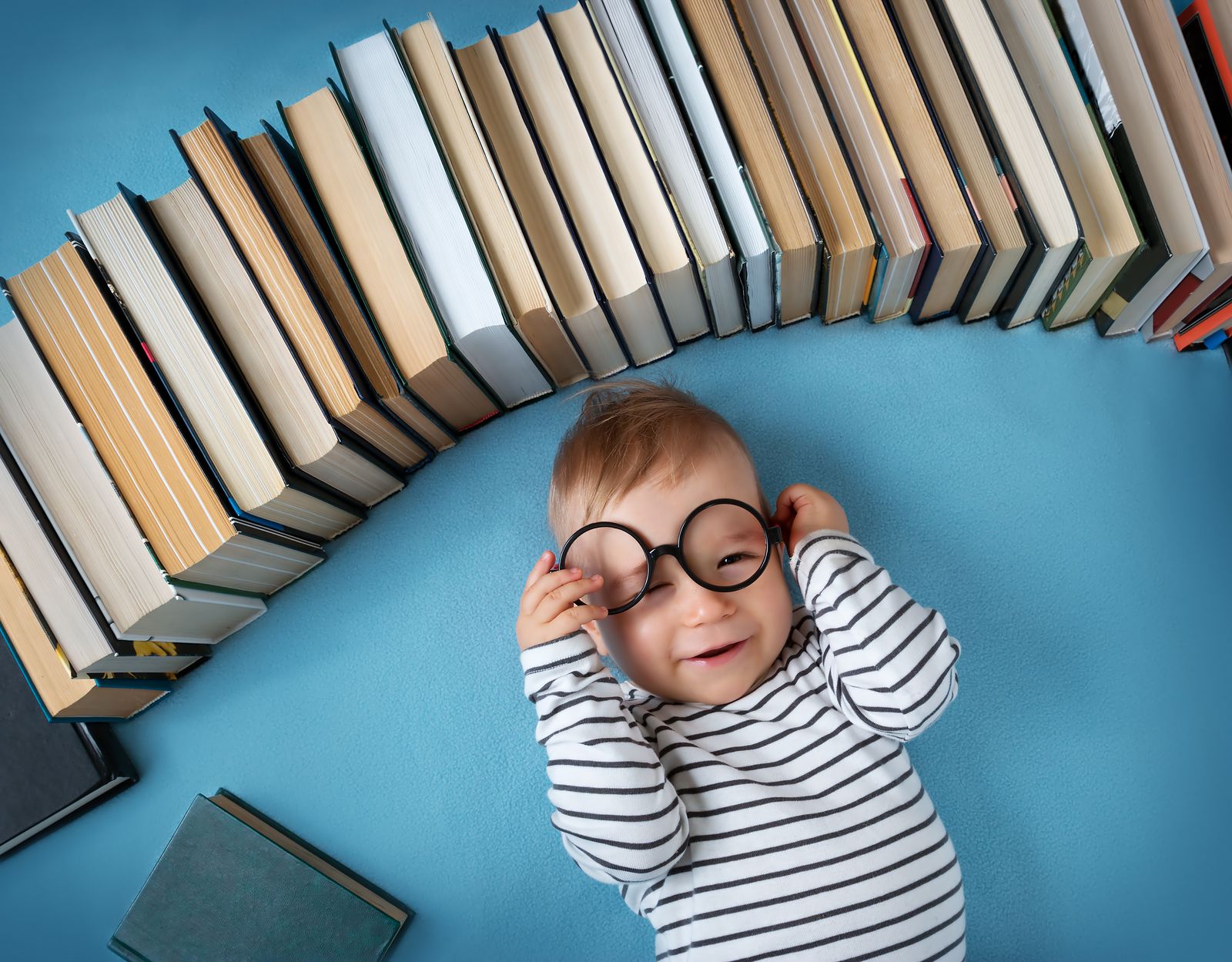 Kleinkind mit Brille unter einem Bogen aus Büchern
