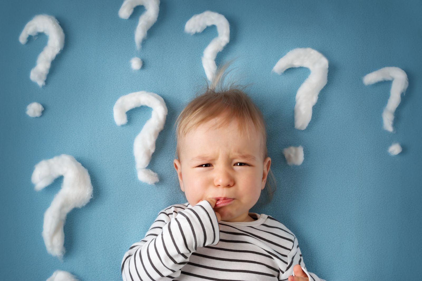 Baby umgeben von Fragezeichen