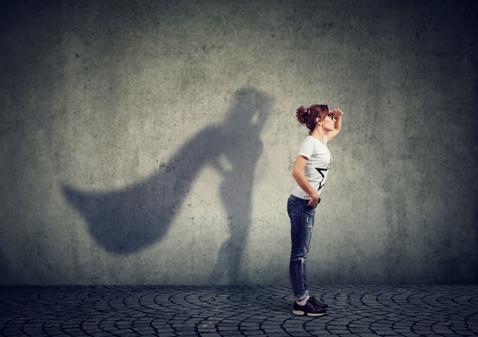 Frau mit Superhelden-Schatten an der Wand